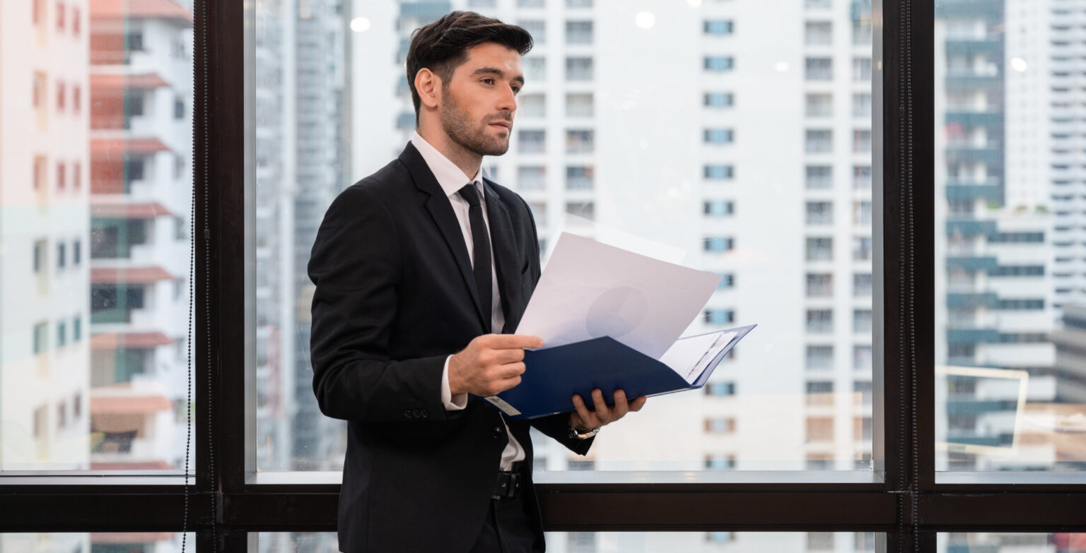 Young caucasian businessman holding financial document and looki